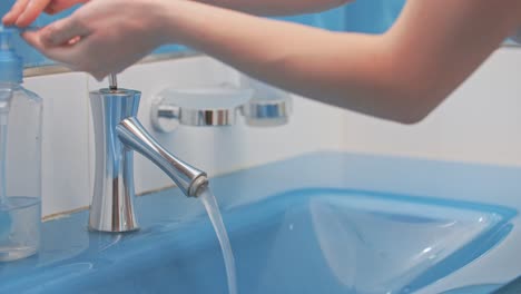 the girl washes her hands, using liquid soap, in a beautiful blue sink