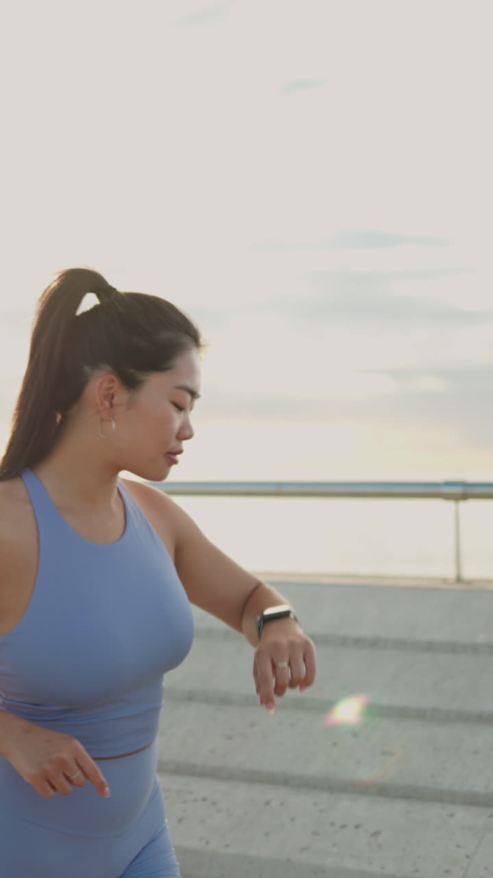 Young Woman Checks Smartwatch Before Running Outdoors