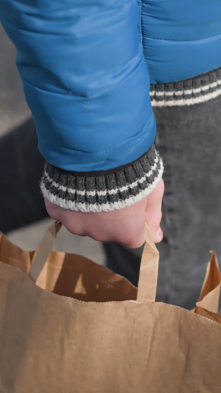 primer plano de piernas caminando en un área residencial, persona sosteniendo una bolsa de papel con sombras visibles en el suelo, con ropa casual, creando una escena urbana dinámica con iluminación suave