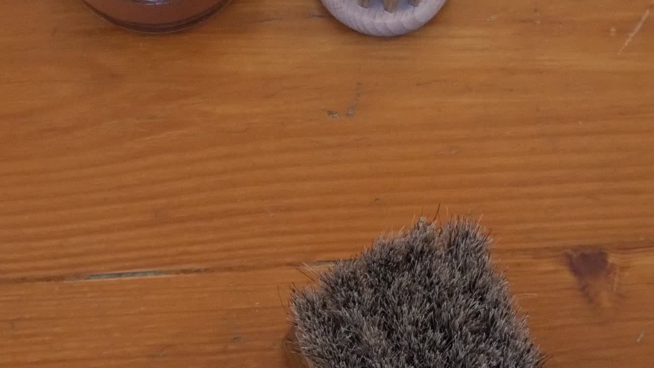 Kartáč na boty a leštidlo pro péči o kůži na dřevěném stole