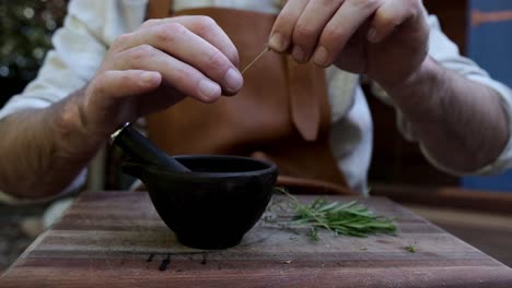 man preparing herbs for cooking with a pestle and mortar