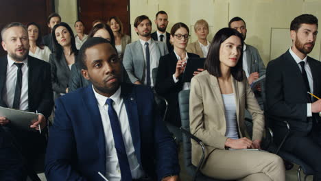 close-up view of multiethnic business people sitting on chairs and listening in a conference room