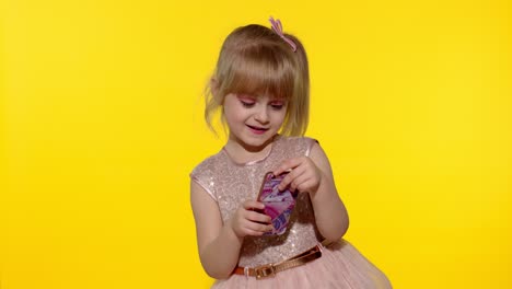 niña usando un teléfono inteligente. niño enviando mensajes de texto en el teléfono electrónico. niño jugando juegos en el teléfono móvil en el estudio