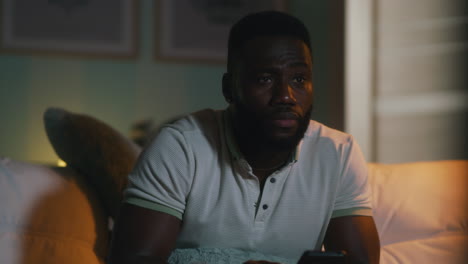 man watching tv and eating popcorn