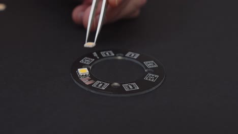 manually placing smd leds with silver tweezers on black pcb