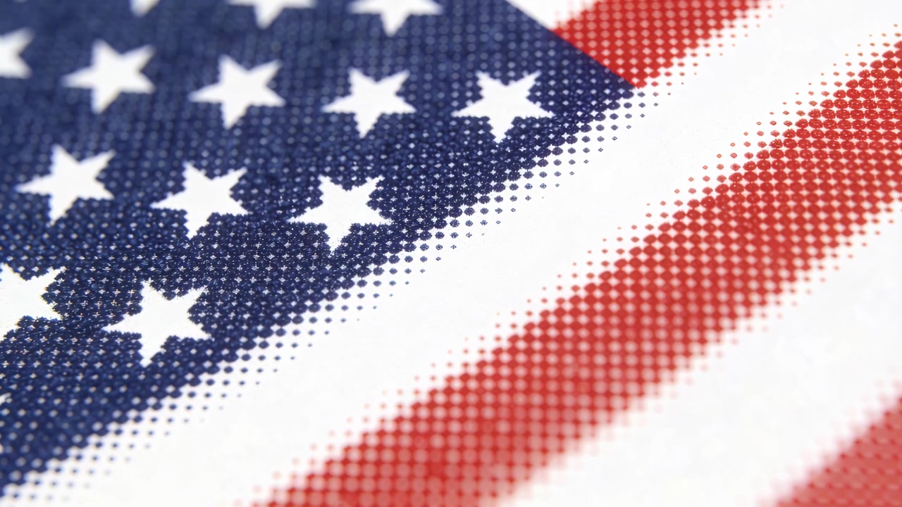 Glimtende amerikansk flagtekstil skifter under en kameraindzoomning i studie, afslører et halvtonemønster i vævningen.
