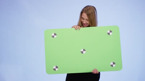 cheerful woman holding oversized blank card on blue background