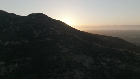 Aerial-view-of-hiking-trail-on-Cowles-Mountain-during-the-sunrise-orbiting-to-reveal-the-city-of-San-Carlos-in-San-Diego-California,-USA