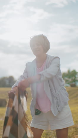 la abuela y la nieta extienden la manta en el campo iluminado por el sol mientras sostienen la correa del perro, la cálida luz del sol crea un efecto brillante mientras se preparan para un acogedor momento al aire libre rodeados de naturaleza