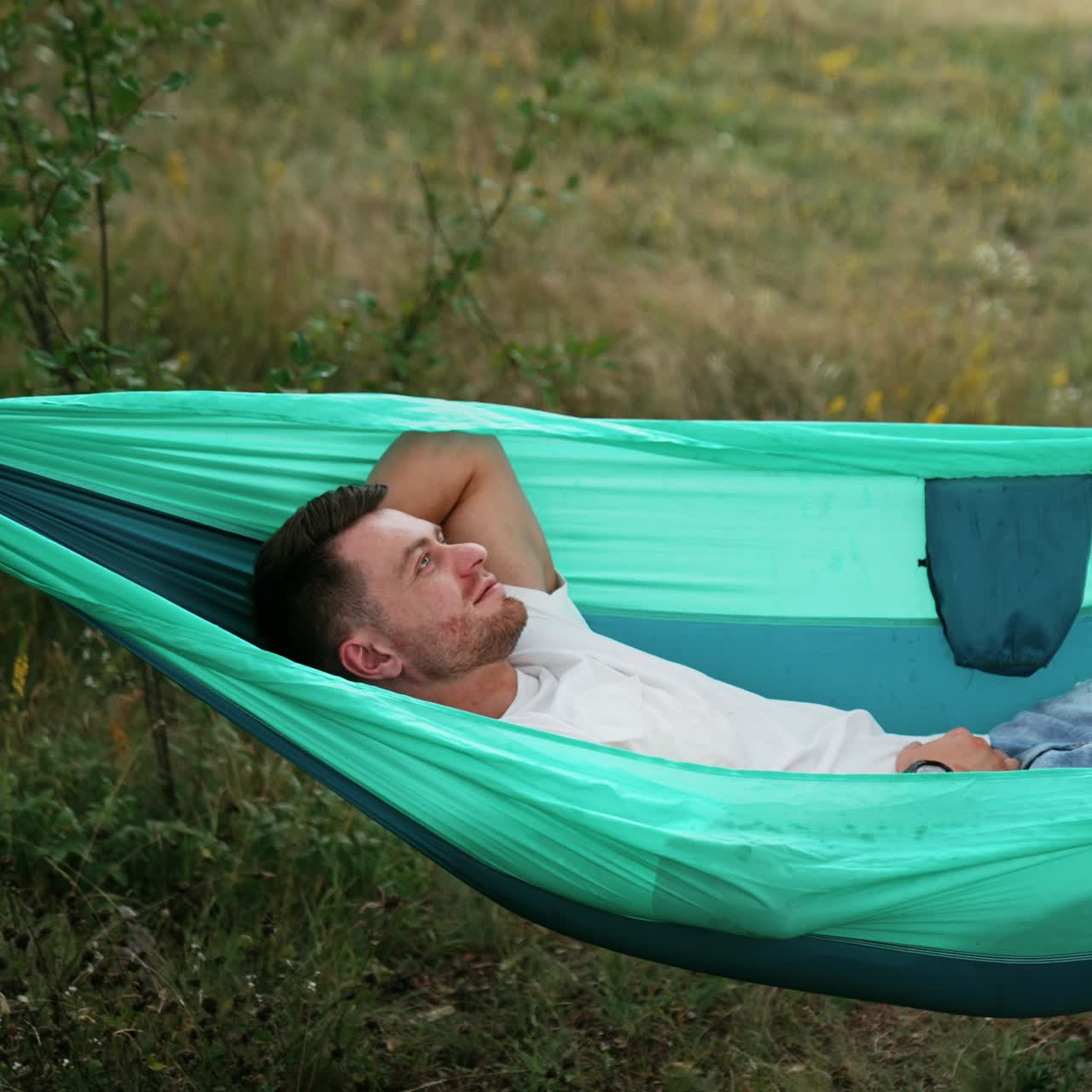 Relaxed Caucasian man swaying in hammock falling asleep. Person having rest in nature