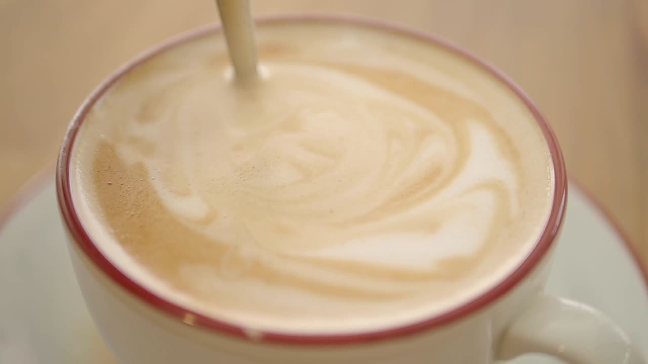 Primo piano di un cucchiaio che mescola Latte Art schiumosa