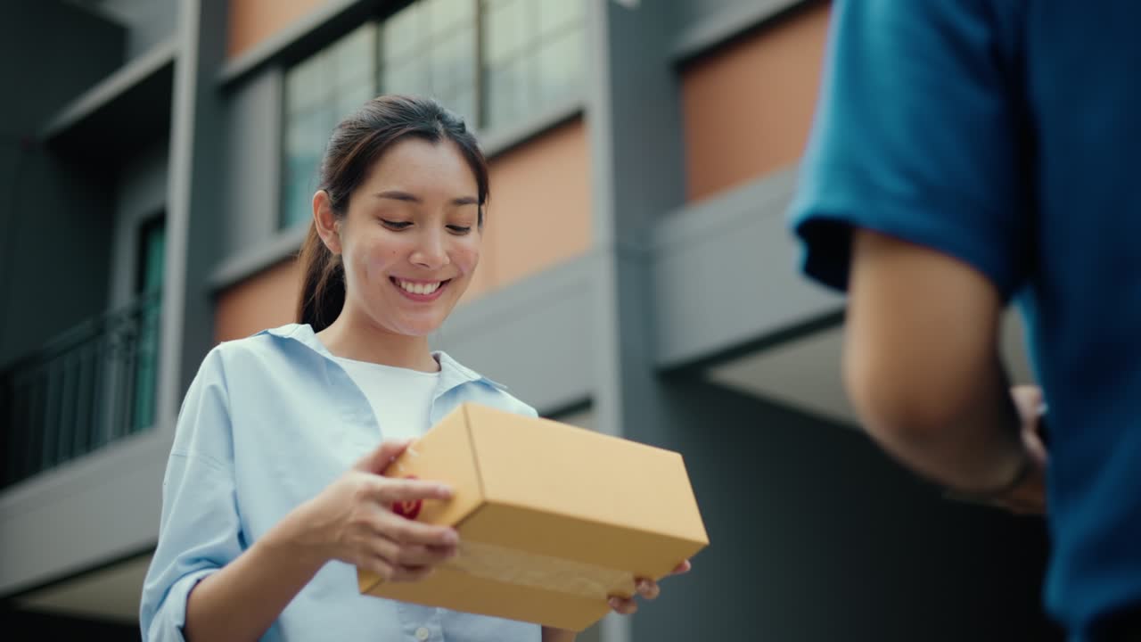 Young woman signing electronic Signature on tablet for agreement of contract digital receiving parcel from blue delivery man from shopping online. Courier man delivering package to destination.