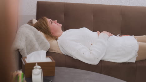 vulnerable visitor lies on cushion gesturing while speaking with specialist in calm therapy environment, tissue box on table adds emotional context, hands expressively move during deep conversation