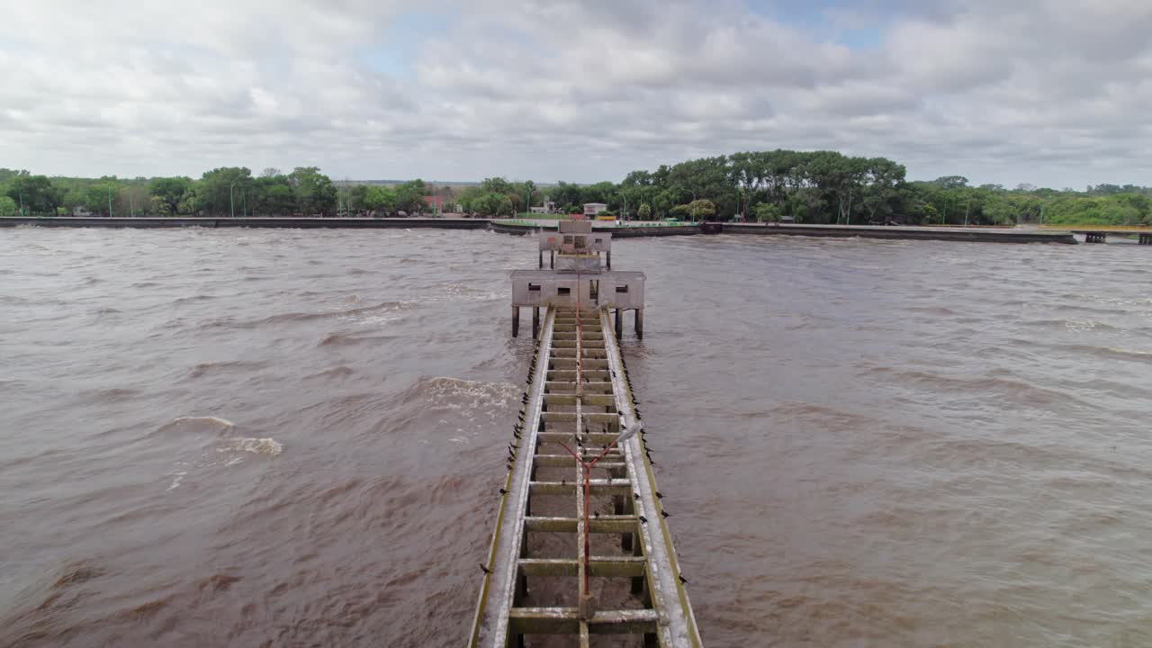 A breathtaking drone shot of a weathered pier stretching into the Rio de La Plata at Punta Lara, Buenos Aires.