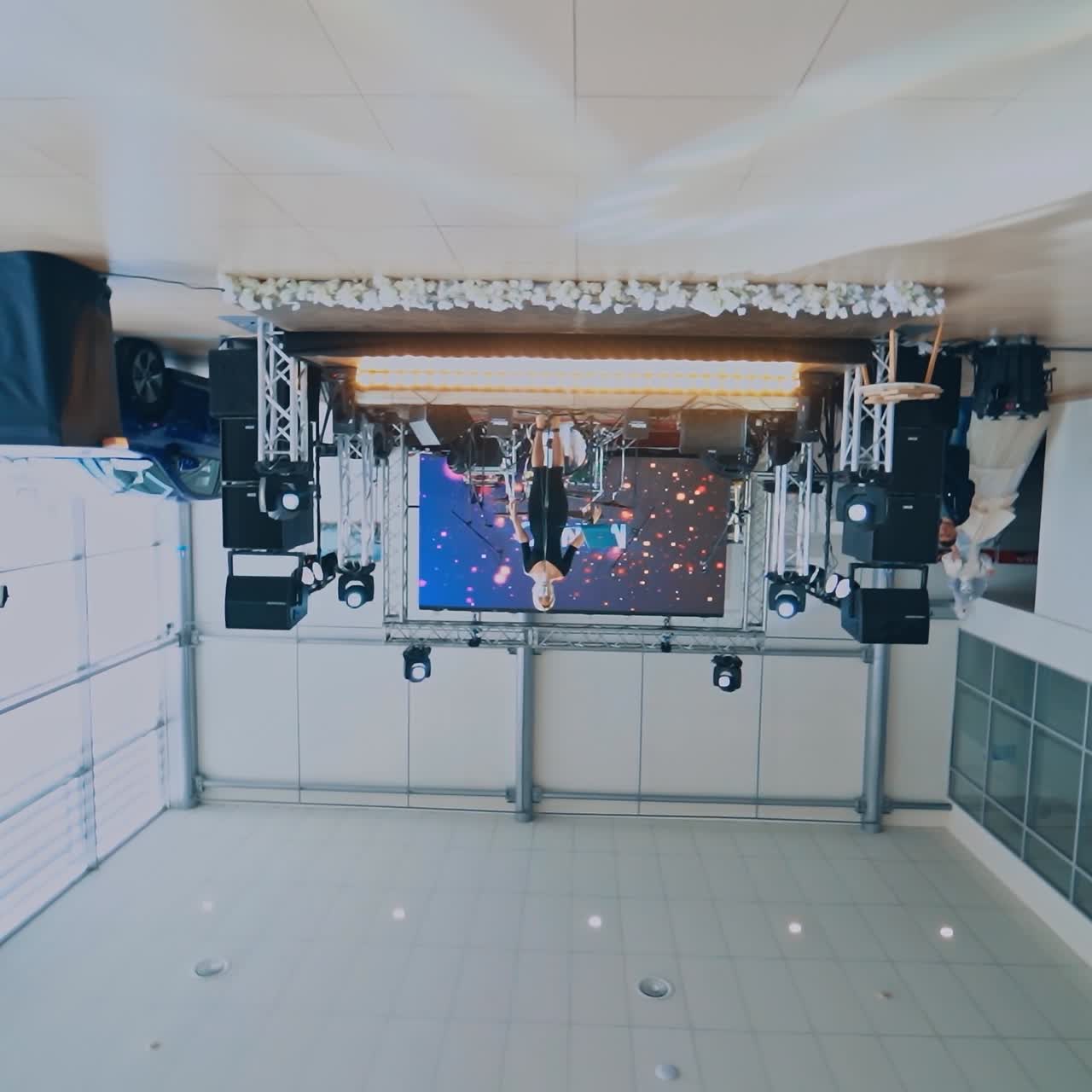 Empty chairs in the hall. Singer at the microphone on the stage. Light show room. Motion camera upside down.