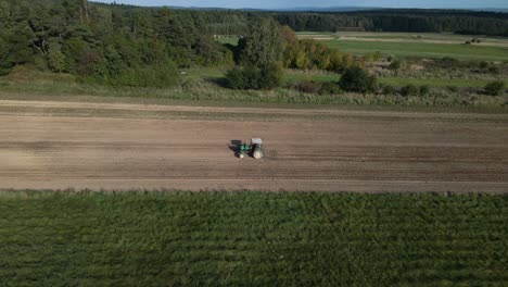 Toma-Aérea-De-Seguimiento-De-Granjero-Con-Tractor-Arando-Campo-Agrícola-En-El-Campo-De-Polonia