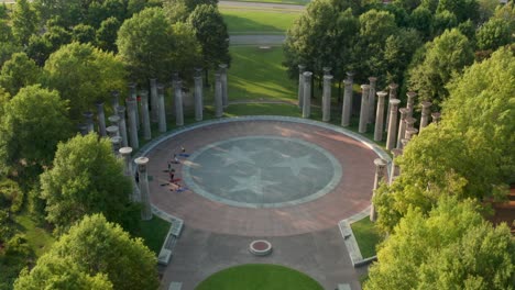 aerial tilt down reveals carillon pillars and people doing yoga