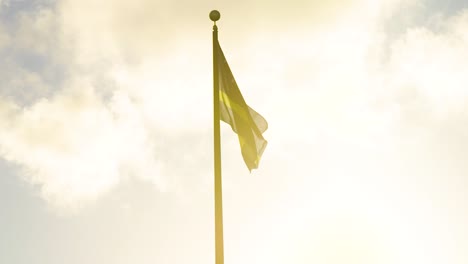 National-flag-of-Curacao,-Caribbean,-raised-atop-a-flag-pole-at-sunset