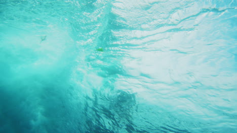 vista trasera bajo el agua de un surfista atrapando una ola empinada en el barril