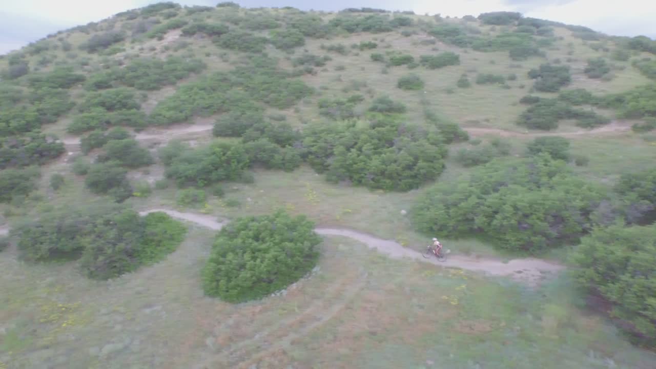 вид с беспилотника на велосипедиста, спускающегося с горы в колорадо