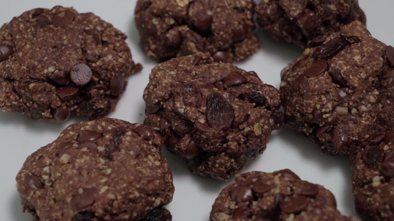 Oatmeal raisin cookies with chocolate chips on white, closeup pan right