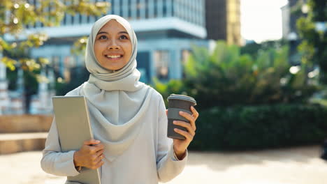 confident muslim woman with laptop and coffee in urban setting