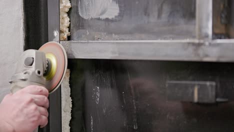 caucasian hand cleaning of welded seams with an angle grinder with a flap disc on welded metal construction close-up with long spark trails, slow motion