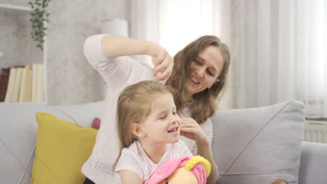 Mom-is-combing-her-cute-beautiful-daughter's-hair.