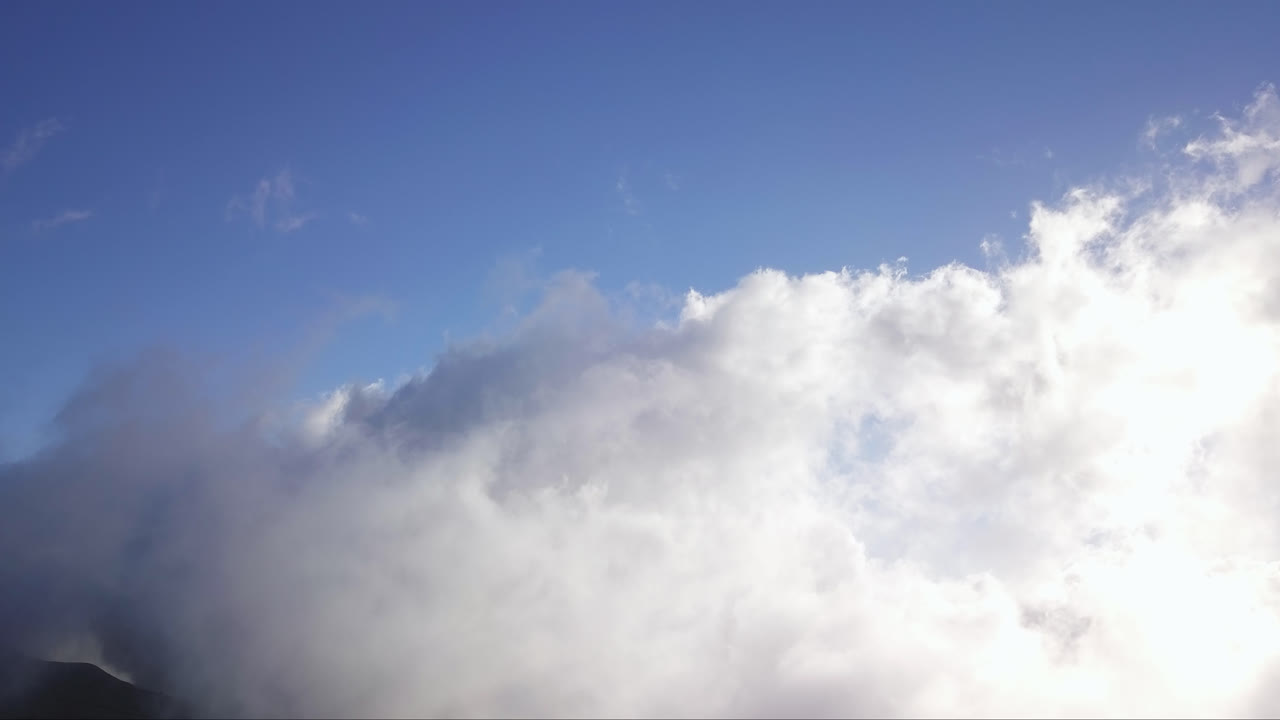 Clouds moving over the slopes of Haleakala volcano in Hawaii at daylight. Wide view