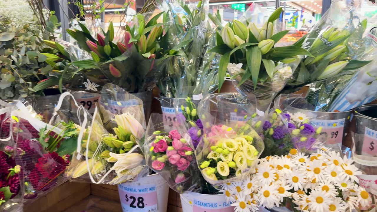 Brightly lit flower market stall with assorted bouquets, camera pans slowly across vibrant floral arrangements