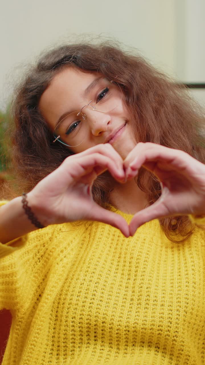 Young child kid girl makes symbol of love showing heart sign to camera express romantic feelings