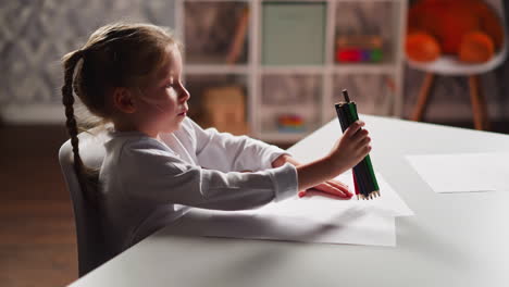 pensive little girl draws lines on paper with crayons bunch