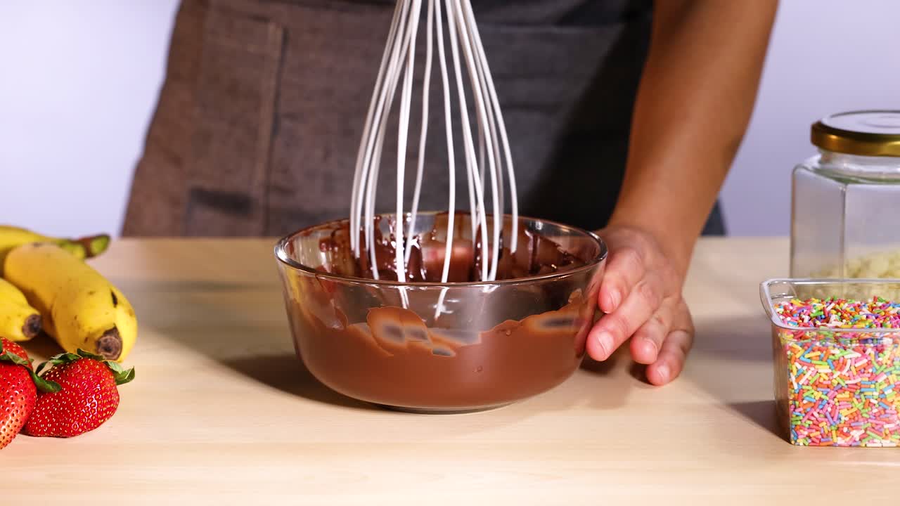 Misturando chocolate com bananas e morangos por perto