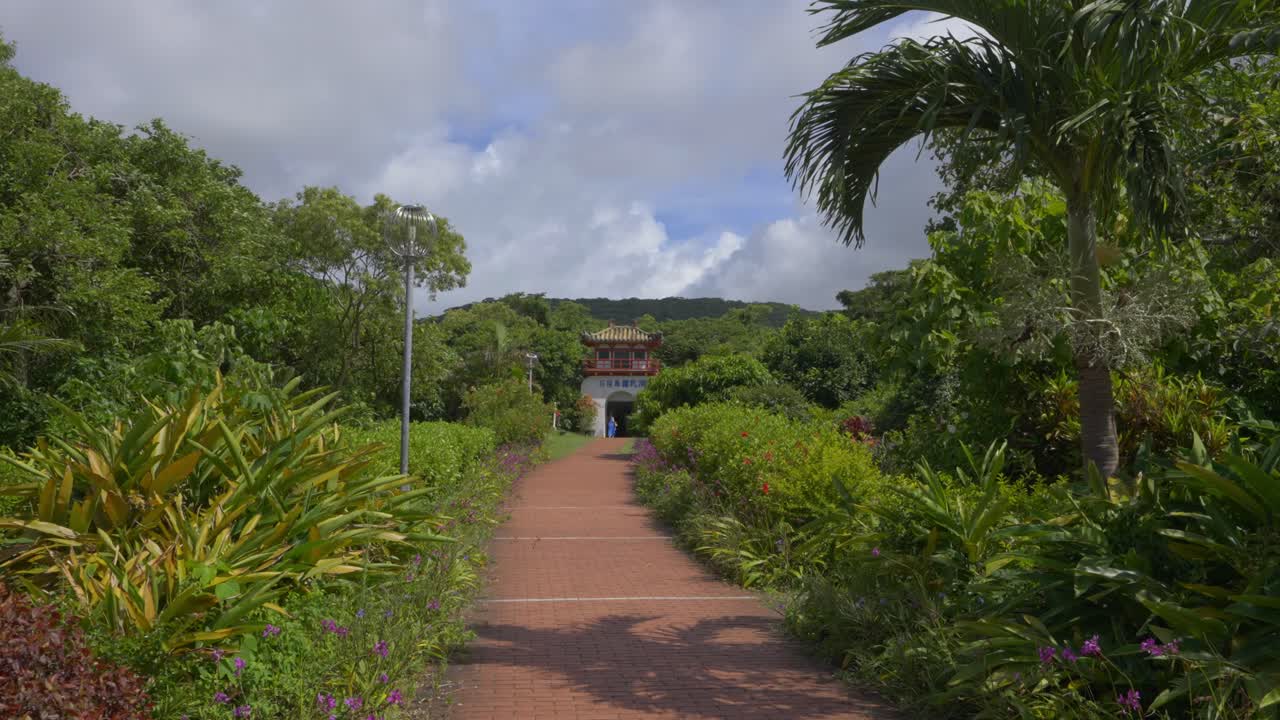Unveil the Ishigaki Cave's entry monument in Japan during the day, harmoniously integrated into the natural environment, as the camera pans forward, offering a view of this captivating location