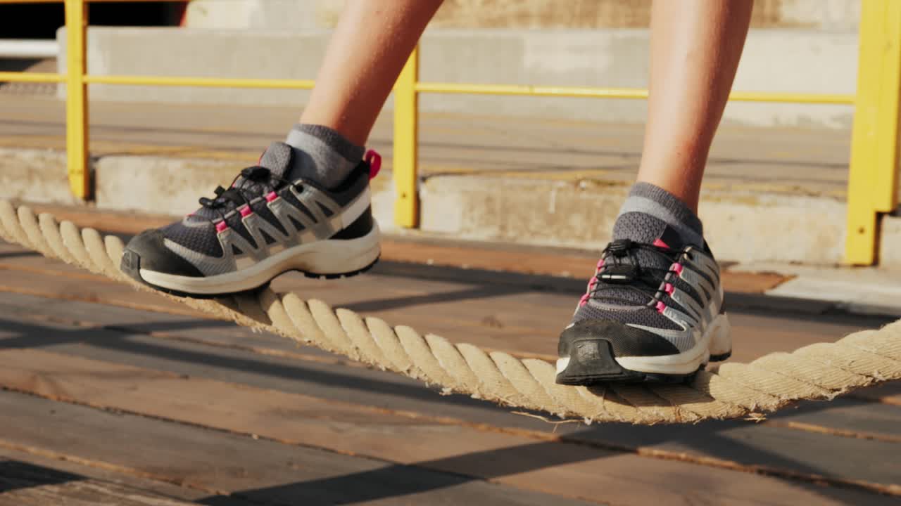 Close-up of feet balancing on a thick rope