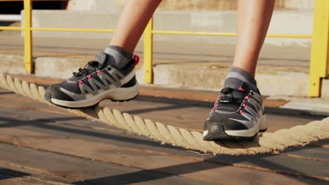 close-up of feet balancing on a thick rope