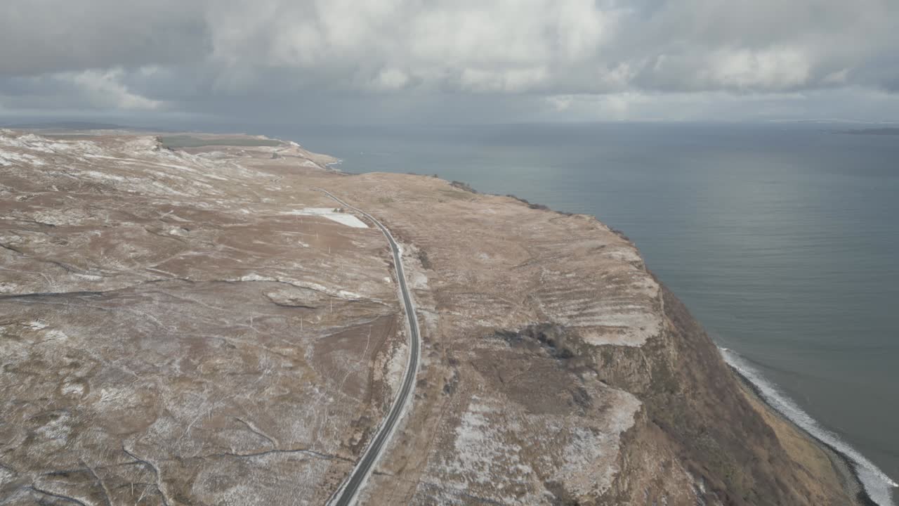 스코틀랜드의 스카이 섬의 스토르의 은이 근처의 절벽을 따라 해안 도로, 구름이 가득한 하늘 아래, 공중에서 볼 수 있습니다.
