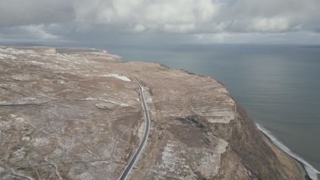 Una-Carretera-Costera-A-Lo-Largo-De-Acantilados-Cerca-Del-Viejo-De-Storr-En-La-Isla-De-Skye,-Escocia,-Bajo-Un-Cielo-Nublado,-Vista-Aérea