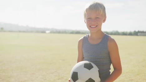 video of happy caucasian boy holding ball on sports field