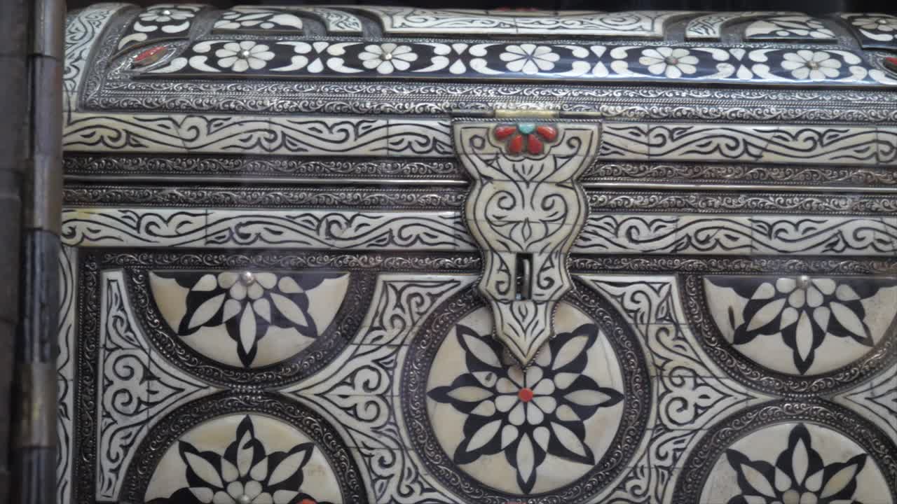 Close-up of a carved ivory storage box with engraving and gems.
