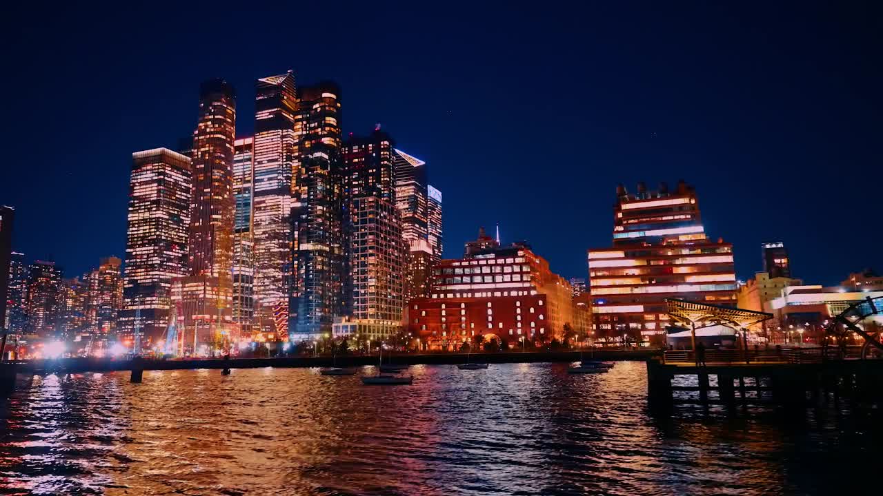 Ánh đèn thành phố trên bờ sông Manhattan. Bờ sông Manhattan được chiếu sáng với những tòa nhà chọc trời và bóng phản chiếu trong đêm tối