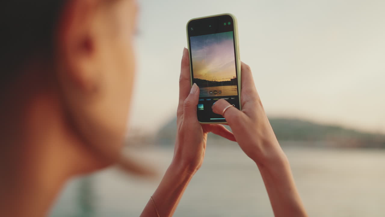 Persona che scatta una foto con uno smartphone al tramonto