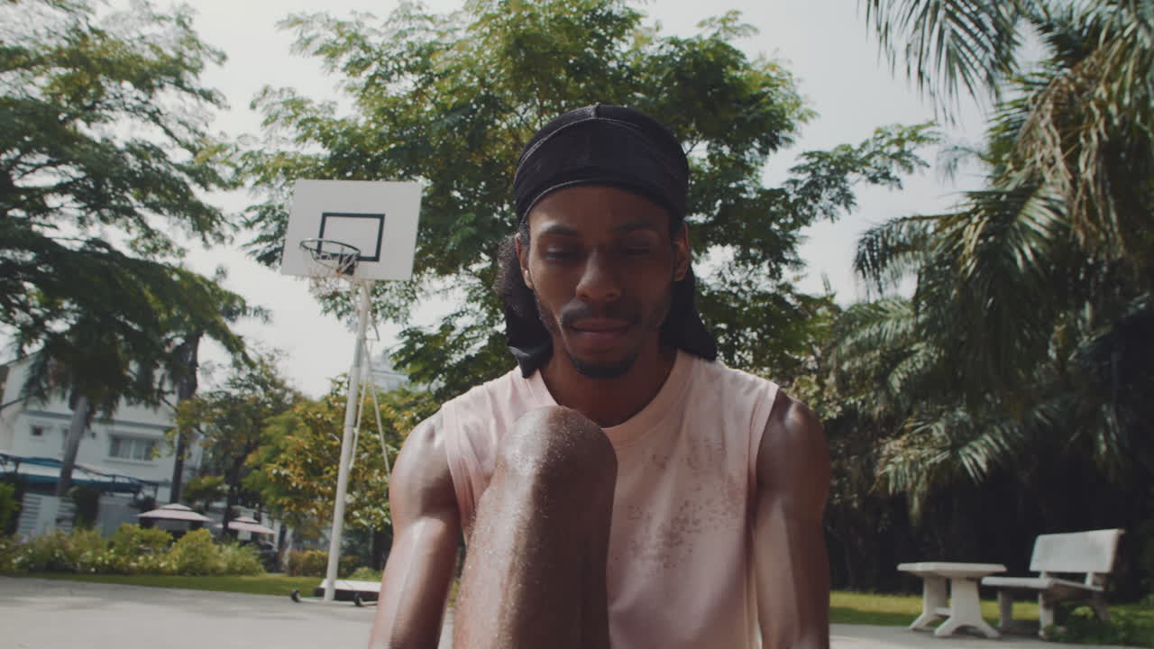 African American Basketball Player Sitting on Court and Tying Shoelaces