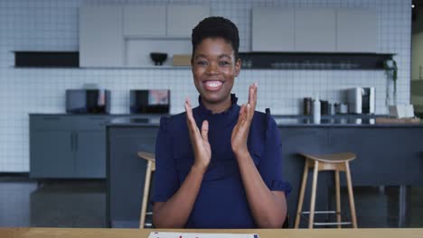 Mujer-De-Negocios-Afroamericana-Teniendo-Video-Chat-Sonriendo-Y-Aplaudiendo-En-La-Cocina-Del-Lugar-De-Trabajo