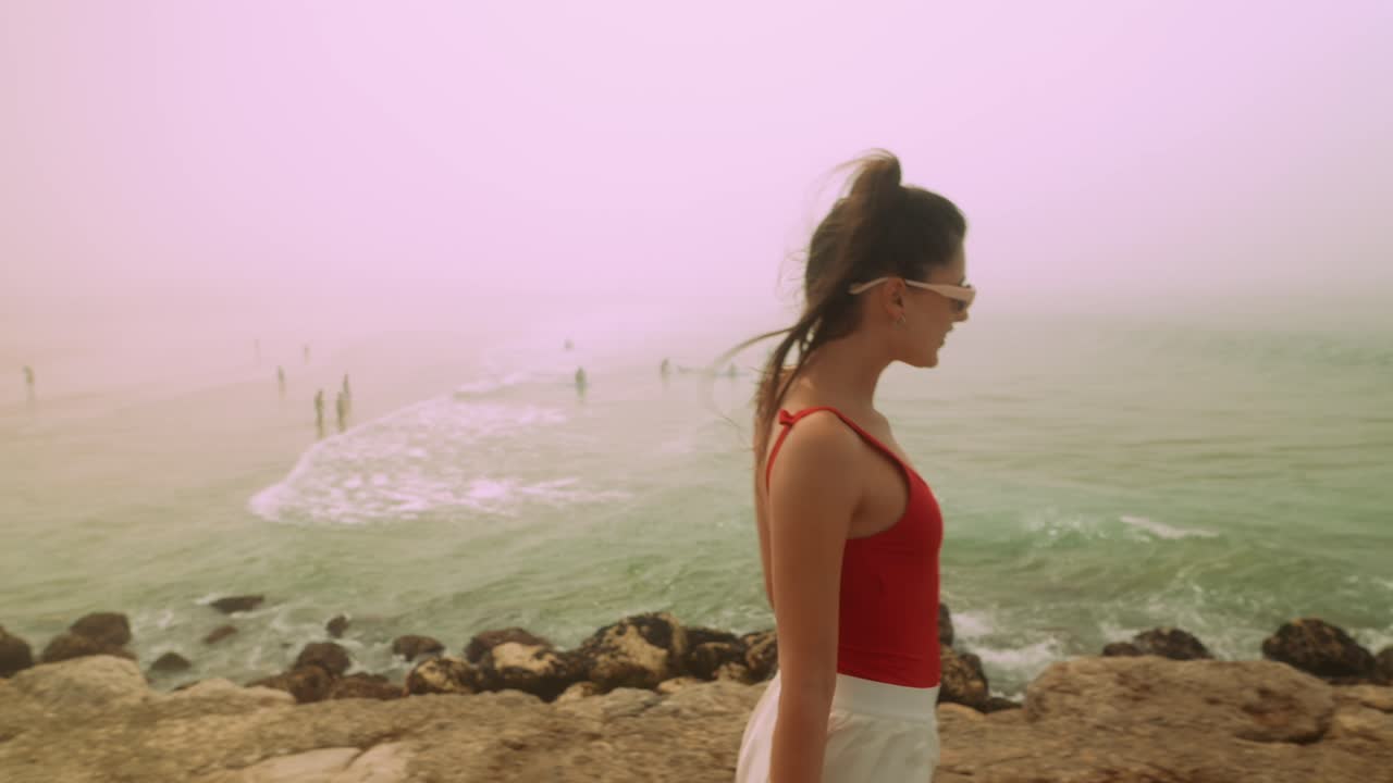 Young Woman Walking Along Rocky Beach on a Foggy Day