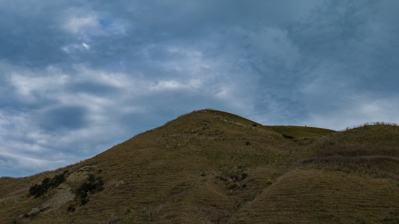 Breathtaking timelapse captures the ever-changing canvas of clouds passing over a serene hillside, offering a mesmerizing journey through the dynamic beauty of the sky and nature's embrace