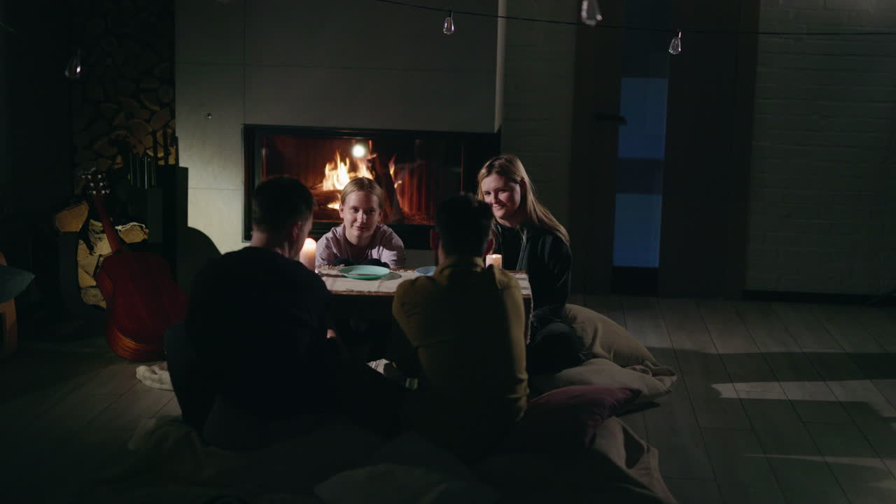 amigos y familia cenando junto a la chimenea.