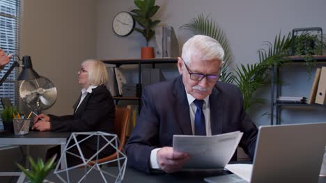 senior elderly business company manager sitting at office reading candidate resume, job interview