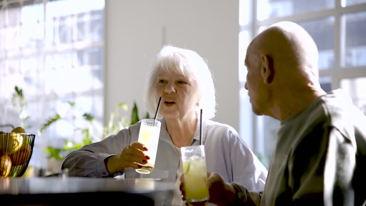 Senior couple drinking limonade and talking while they are sitting in a bar at sunset
