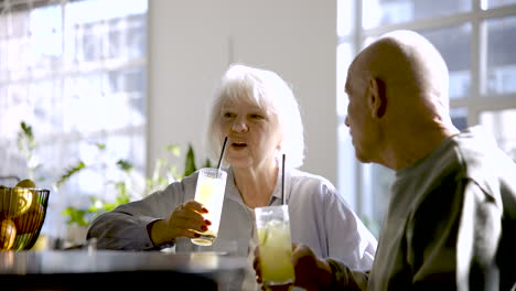 senior couple drinking limonade and talking while they are sitting in a bar at sunset